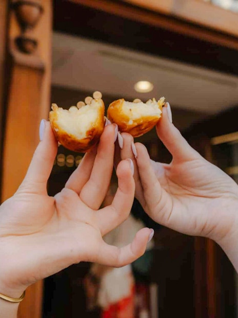 Hands holding pastel de nata on Lisbon food tour.