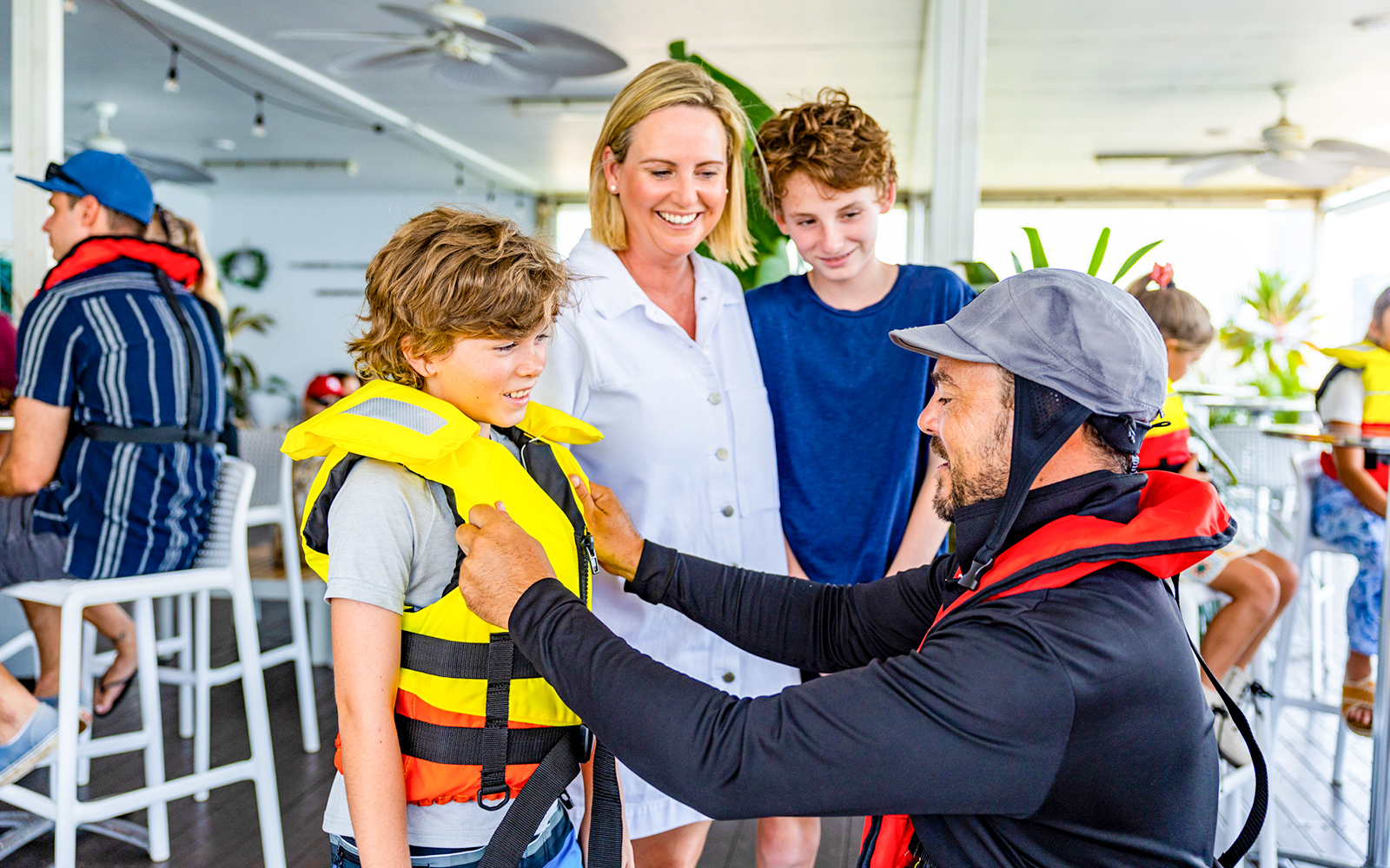Crew member assists child with life vest before Gold Coast jet boat ride.