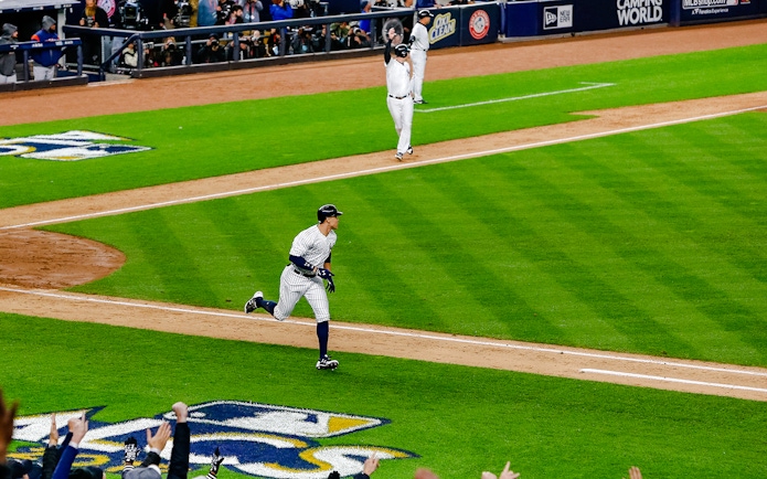 Yankees player running bases at Yankee Stadium during a game.