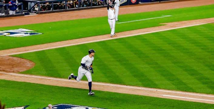 Yankees player running bases at Yankee Stadium during a game.
