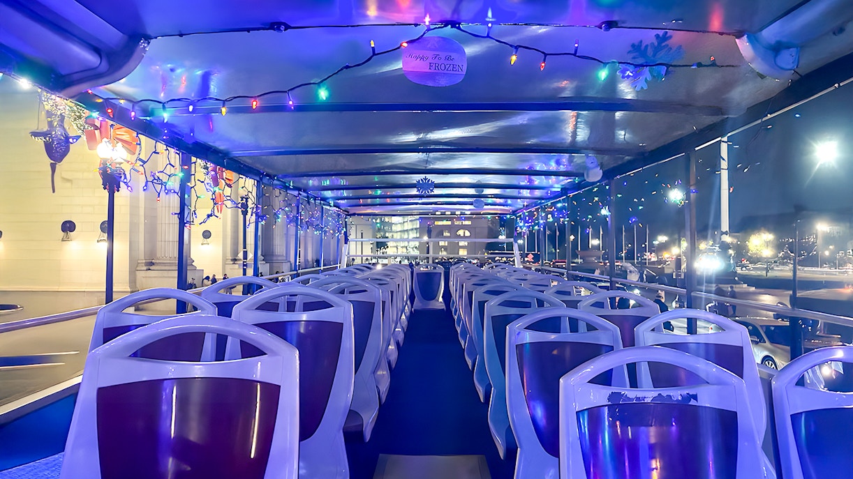 Big Bus interior decorated with Christmas lights for a holiday tour at night.