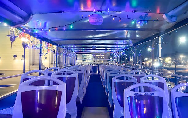 Big Bus interior decorated with Christmas lights for a holiday tour at night.