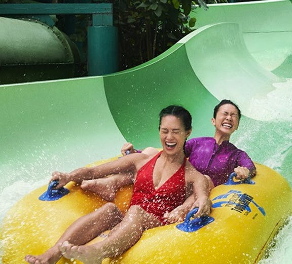 Two people enjoying a water slide ride at Sentosa with the Fun Pass.