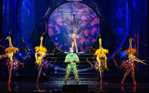 Performers in colorful costumes on stage during The Magic Flute opera.