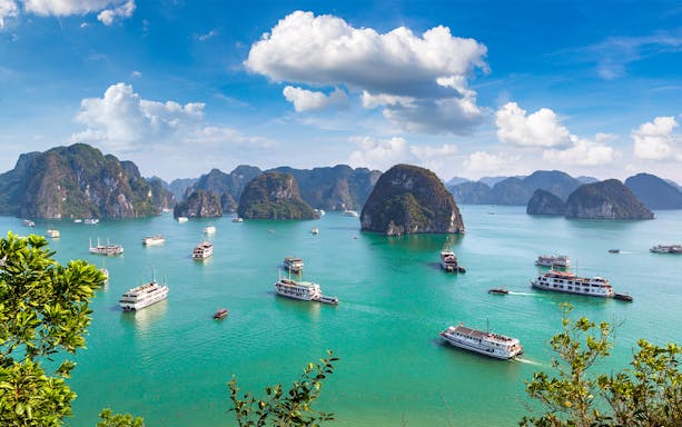 Cruise ships sailing among limestone islands in Halong Bay, Vietnam.