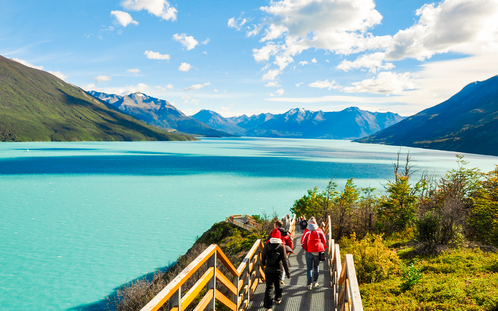 Tourists walking on a pathway with Perito Moreno Glacier and Lago Argentino in Patagonia, Argentina.