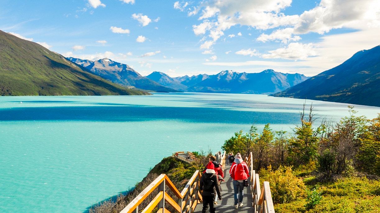Tourists walking on a pathway with Perito Moreno Glacier and Lago Argentino in Patagonia, Argentina.