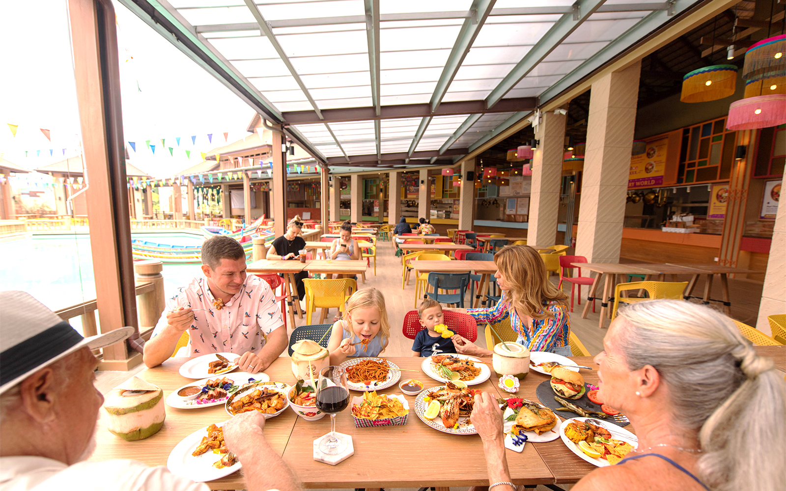 Family dining at a colorful outdoor restaurant in a tropical setting.