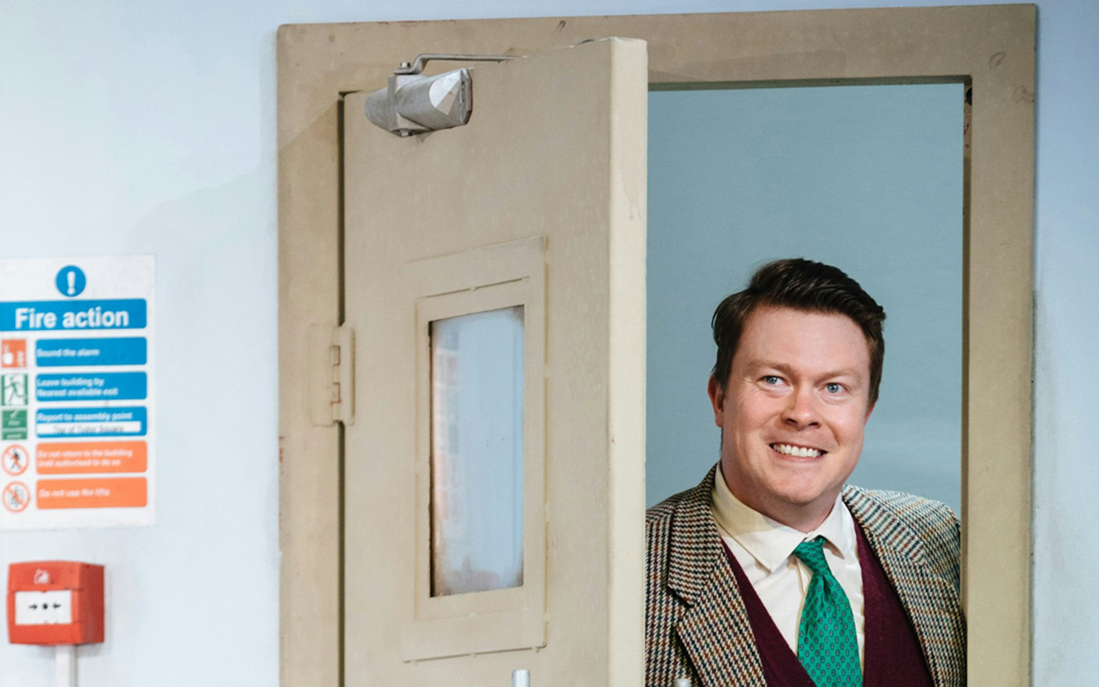 Man smiling while standing in a doorway, related to "Accidental Death of an Anarchist" tickets.