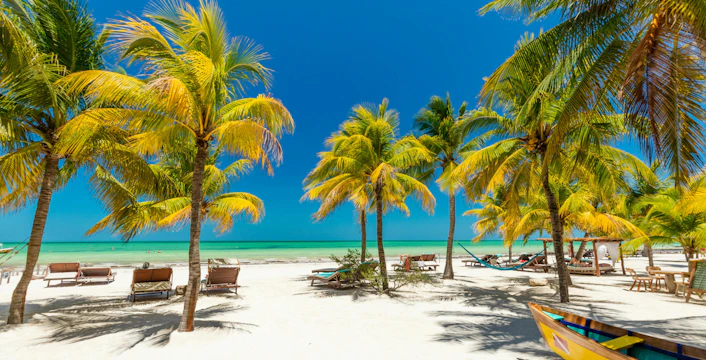 Tropical beach with palm trees and hammocks on Isla Holbox, Mexico.