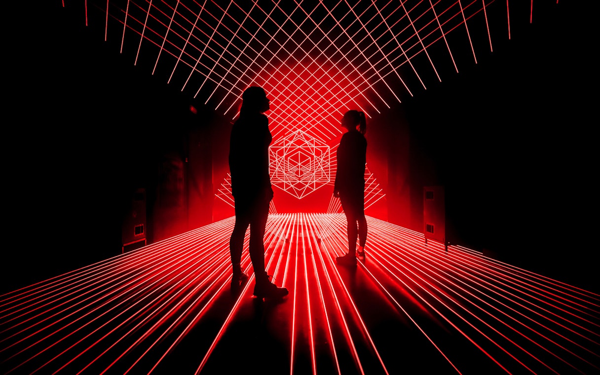 Tourists surrounded by red laser lights at Amaze Amsterdam.