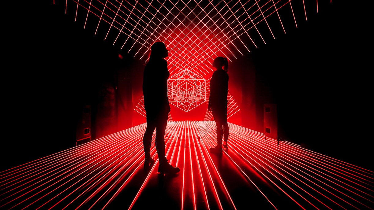 Tourists surrounded by red laser lights at Amaze Amsterdam.