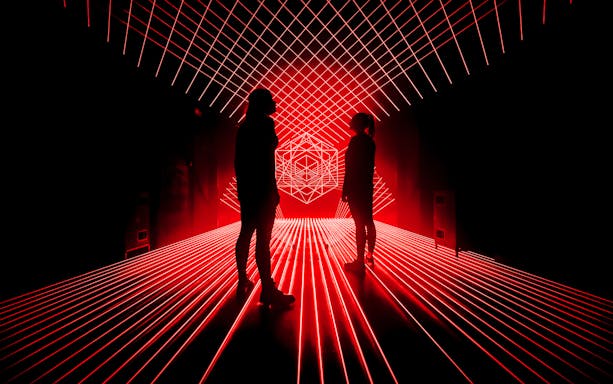 Tourists surrounded by red laser lights at Amaze Amsterdam.