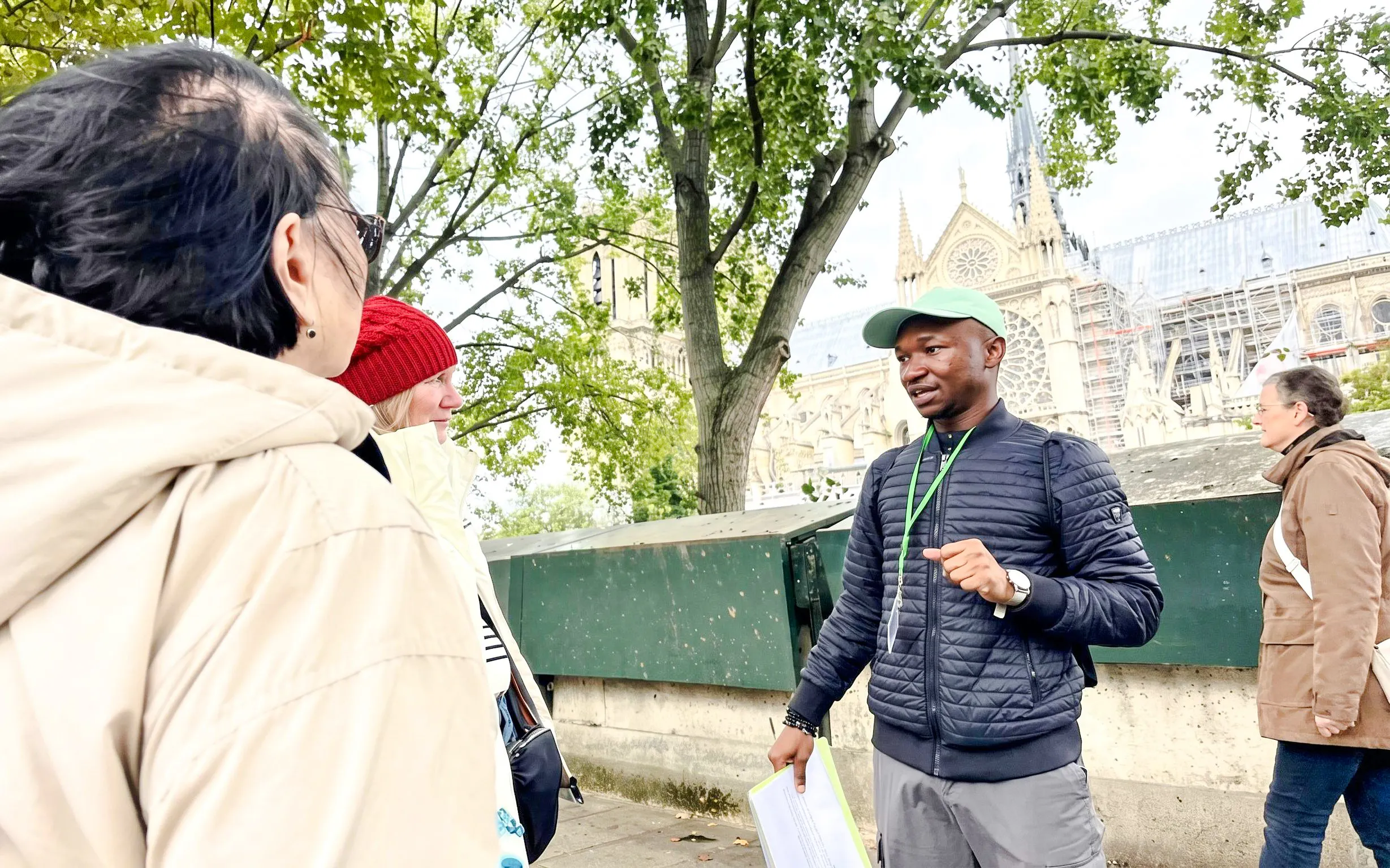 Tour guide explaining Notre-Dame's history to visitors in Paris.
