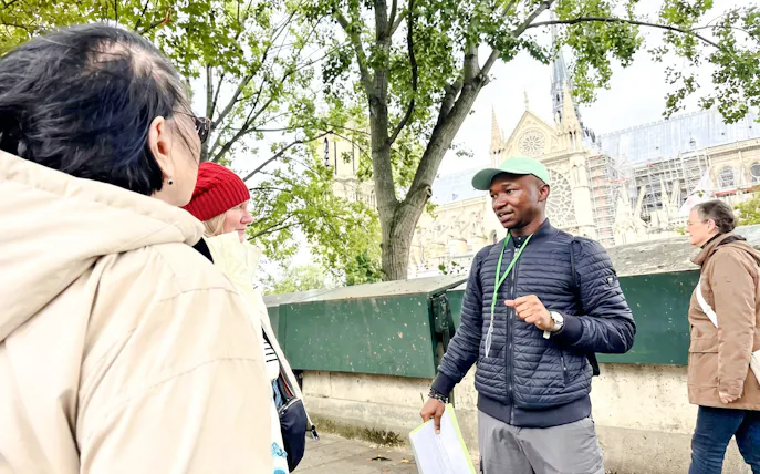Tour guide explaining Notre-Dame's history to visitors in Paris.