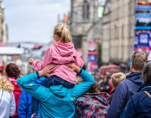 Performers on stage at Edinburgh Fringe Festival, Scotland, with audience in background.