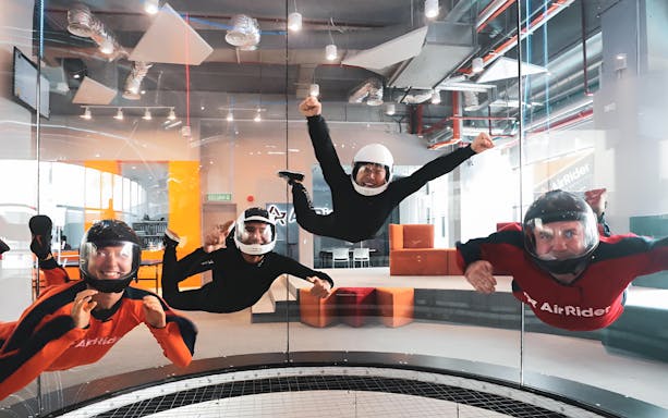 Indoor skydiving group with instructor in wind tunnel.