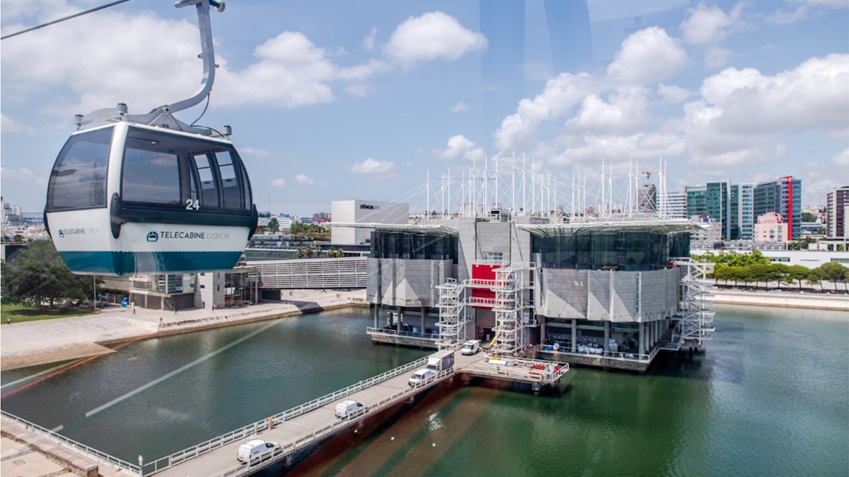 Lisbon Oceanarium with Telecabine cable car over water, cityscape in background.
