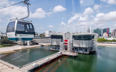 Lisbon Oceanarium with Telecabine cable car over water, cityscape in background.