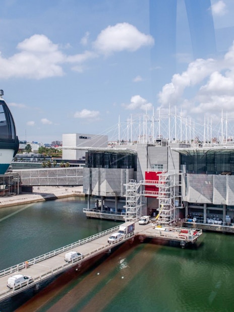 Lisbon Oceanarium with Telecabine cable car over water, cityscape in background.