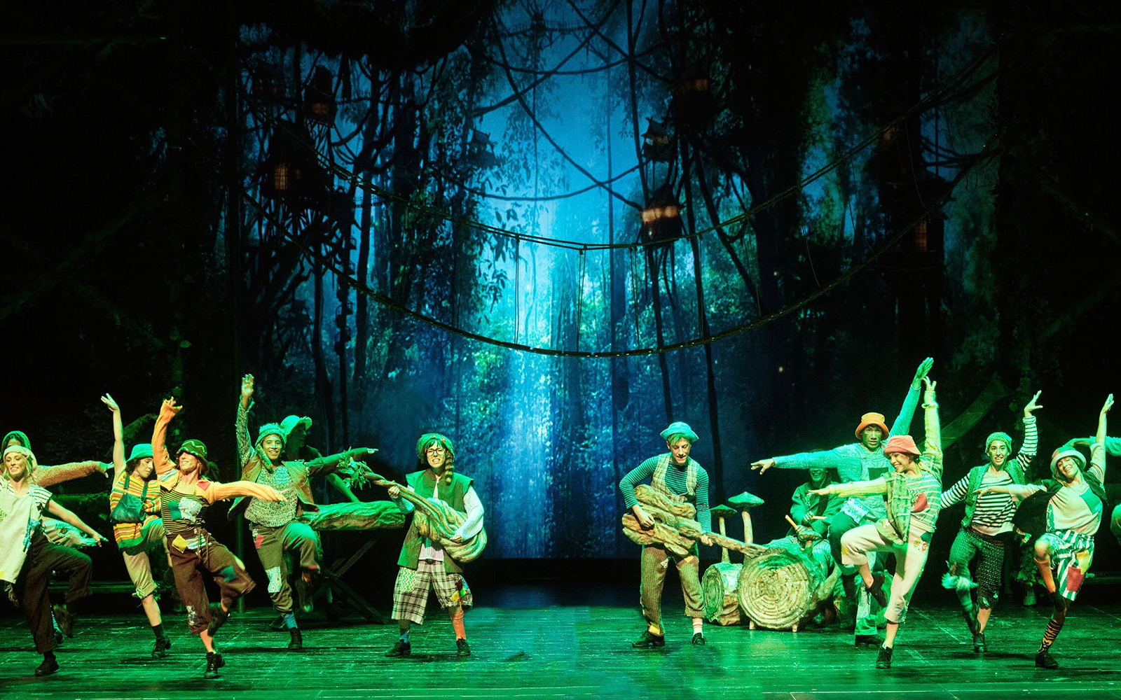 Performers dancing in a forest-themed set during "Peter, El Musical" show.