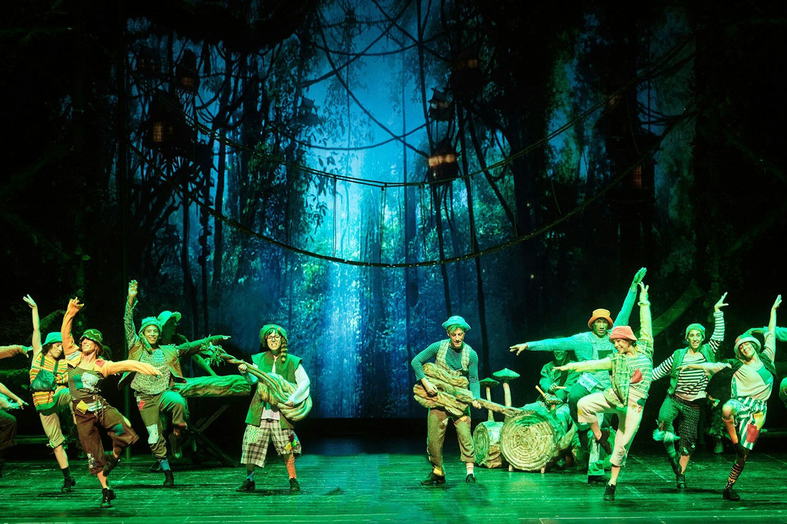 Performers dancing in a forest-themed set during "Peter, El Musical" show.