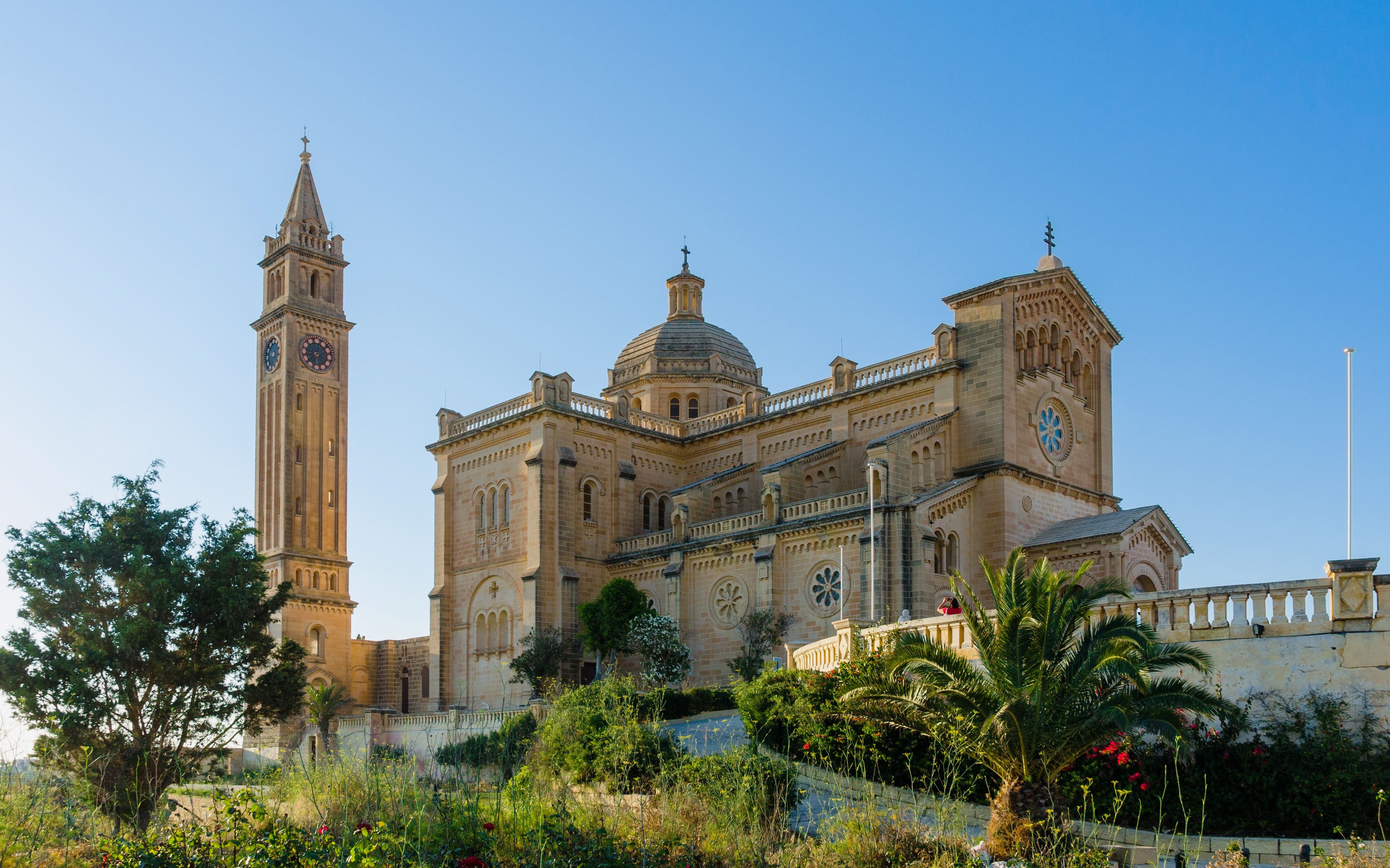 Basilica of Ta' Pinu with bell tower near Għarb, Gozo, under clear blue sky.