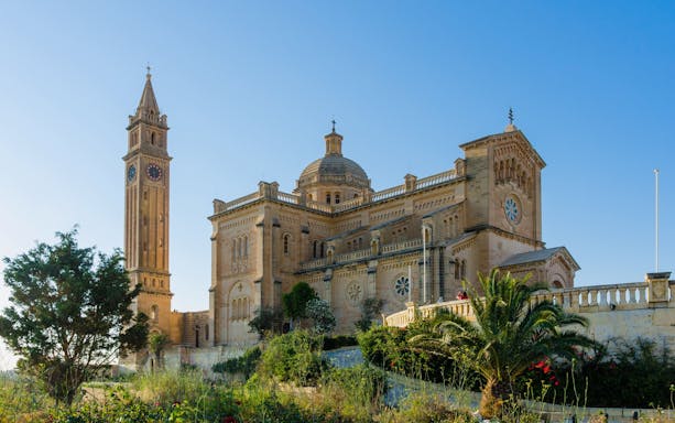 Basilica of Ta' Pinu with bell tower near Għarb, Gozo, under clear blue sky.