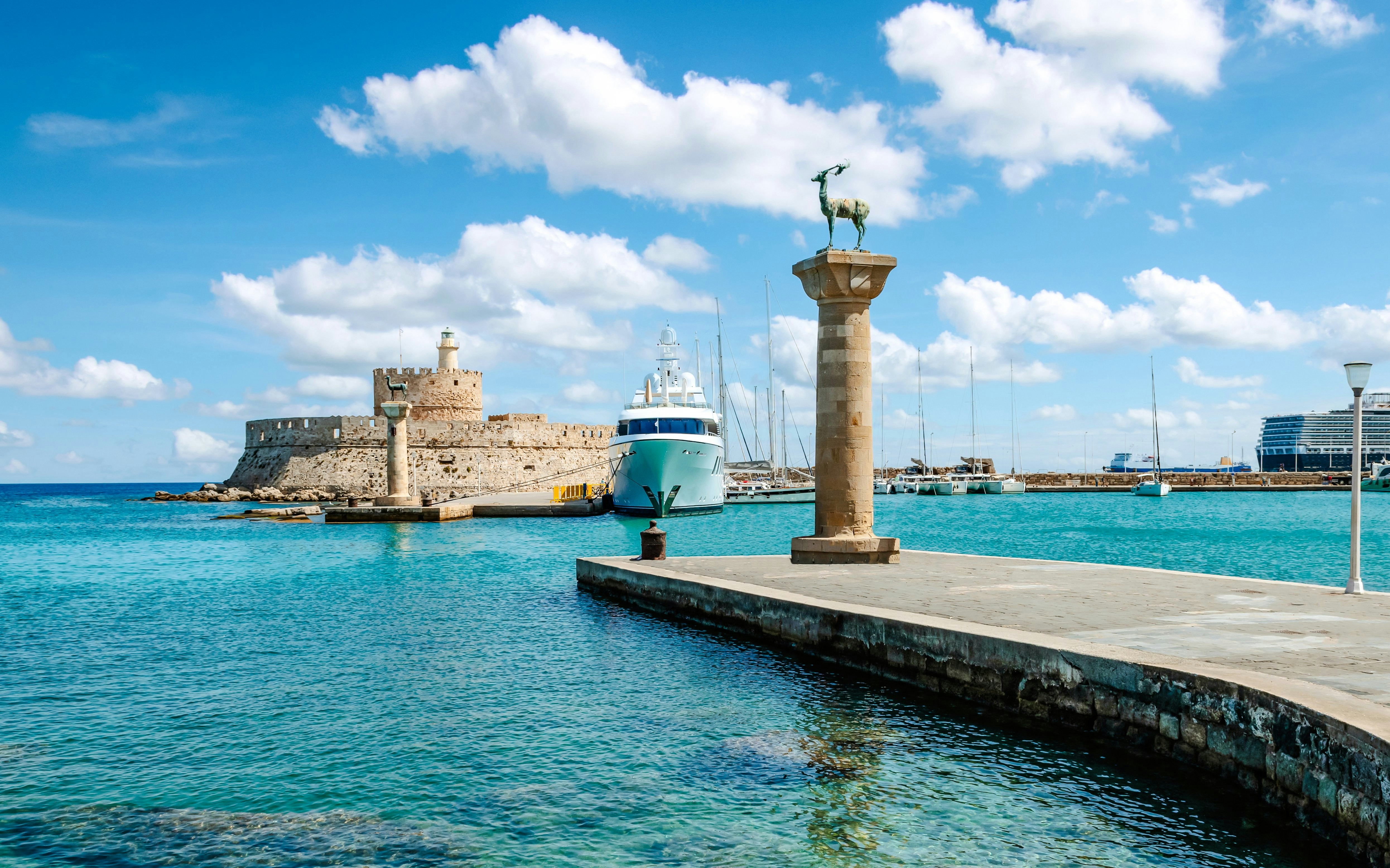 Mandraki Harbor in Rhodes, Greece with medieval fort and deer statue.