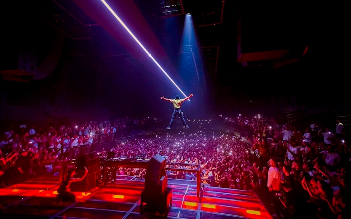 Performer on stage with crowd and lights at Fisher UNVRS, Ibiza concert.