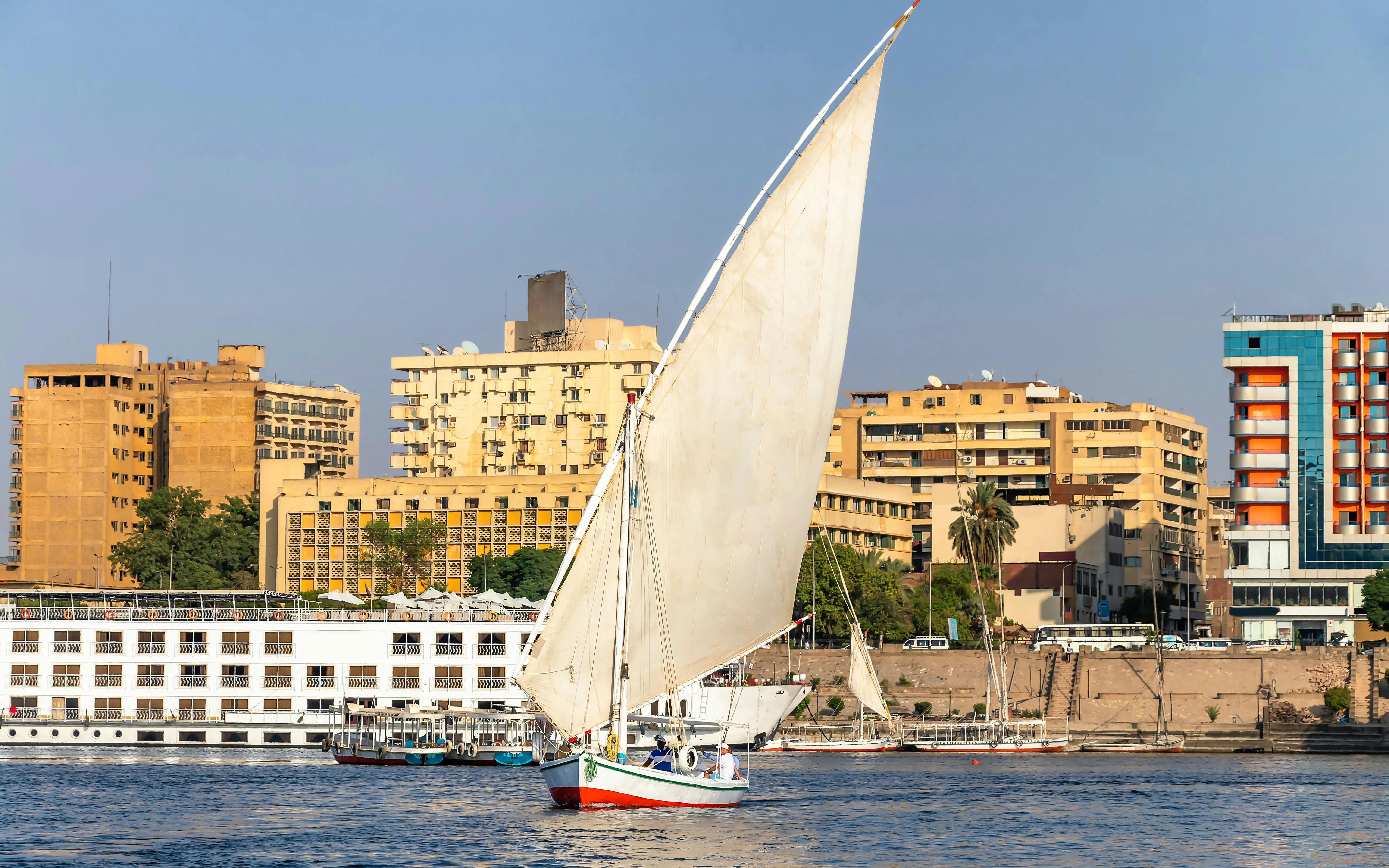 Felucca boat sailing on the Nile River with Cairo cityscape in the background.