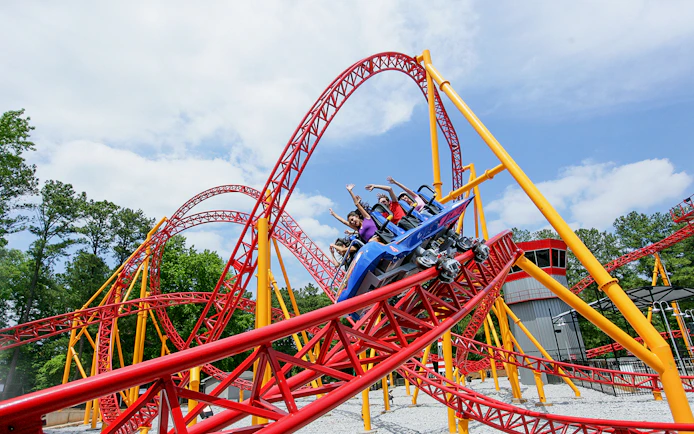 Roller coaster at Six Flags Over Georgia with riders on a red and yellow track.