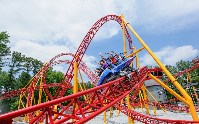 Roller coaster at Six Flags Over Georgia with riders on a red and yellow track.