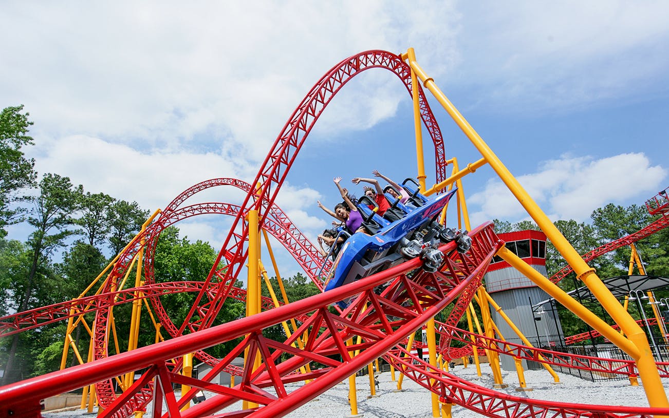 Roller coaster at Six Flags Over Georgia with riders on a red and yellow track.
