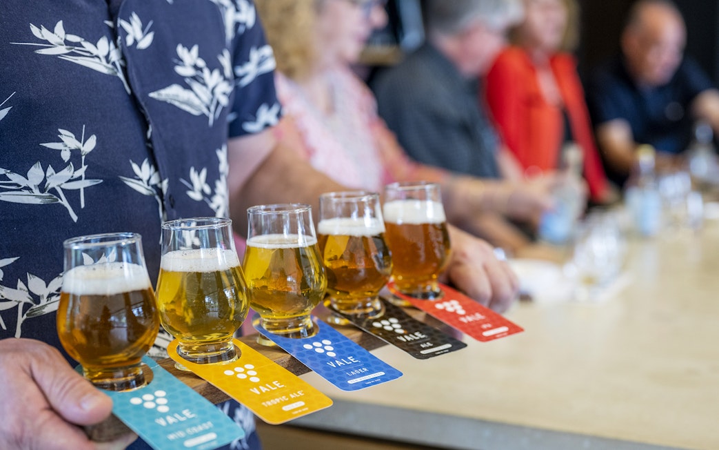 Beer tasting flight at McLaren Vale with various brews on a wooden paddle.