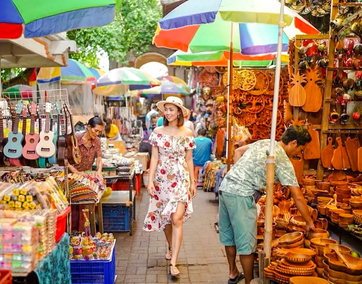Bali market scene with colorful umbrellas, local crafts, and a woman exploring stalls.