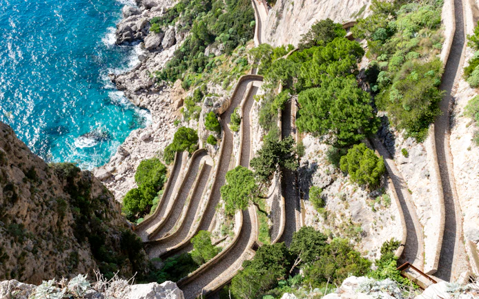 Via Krupp switchback path on Capri, Italy, with coastal cliffs and turquoise sea.