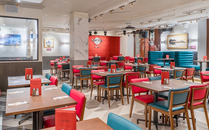 Dining area at Hard Rock Cafe Milan with red and blue seating and iconic decor.