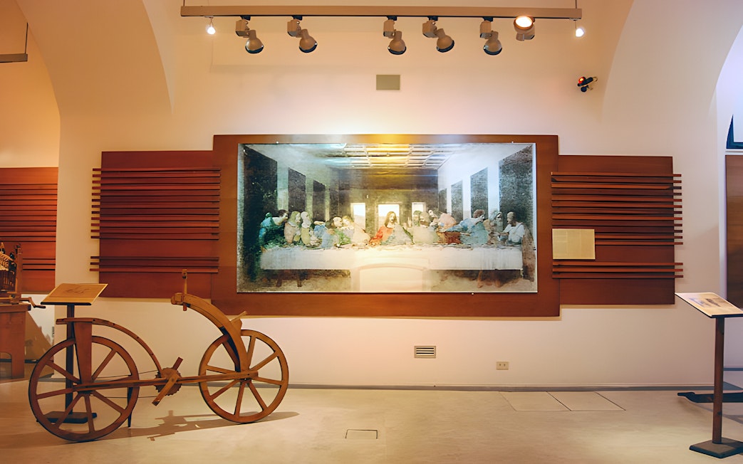 Exhibit of Leonardo da Vinci's Last Supper and wooden bicycle at museum.