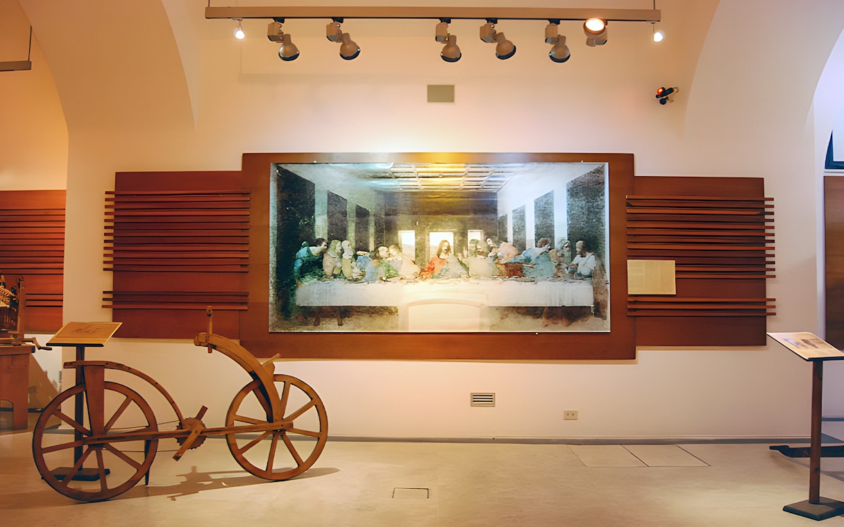 Exhibit of Leonardo da Vinci's Last Supper and wooden bicycle at museum.