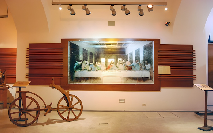 Exhibit of Leonardo da Vinci's Last Supper and wooden bicycle at museum.