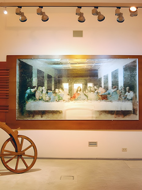 Exhibit of Leonardo da Vinci's Last Supper and wooden bicycle at museum.
