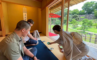 Tea ceremony in Kanazawa with participants seated in a traditional room overlooking a garden.