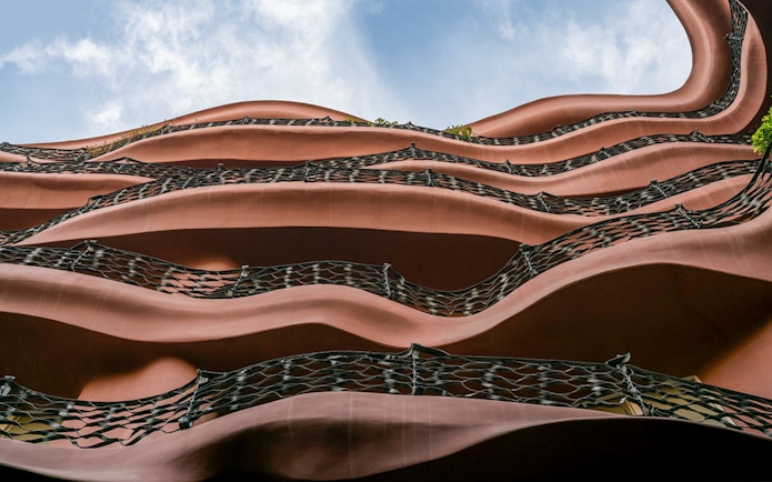 Wavy iron balconies of Casa Mila in Barcelona against a blue sky.