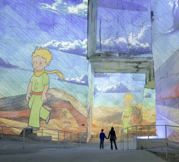 Little Prince projections at Carrières des Lumières exhibition, featuring visitors exploring the illuminated quarry.