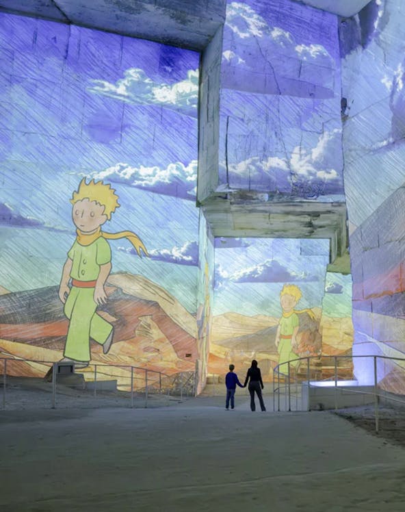 Little Prince projections at Carrières des Lumières exhibition, featuring visitors exploring the illuminated quarry.