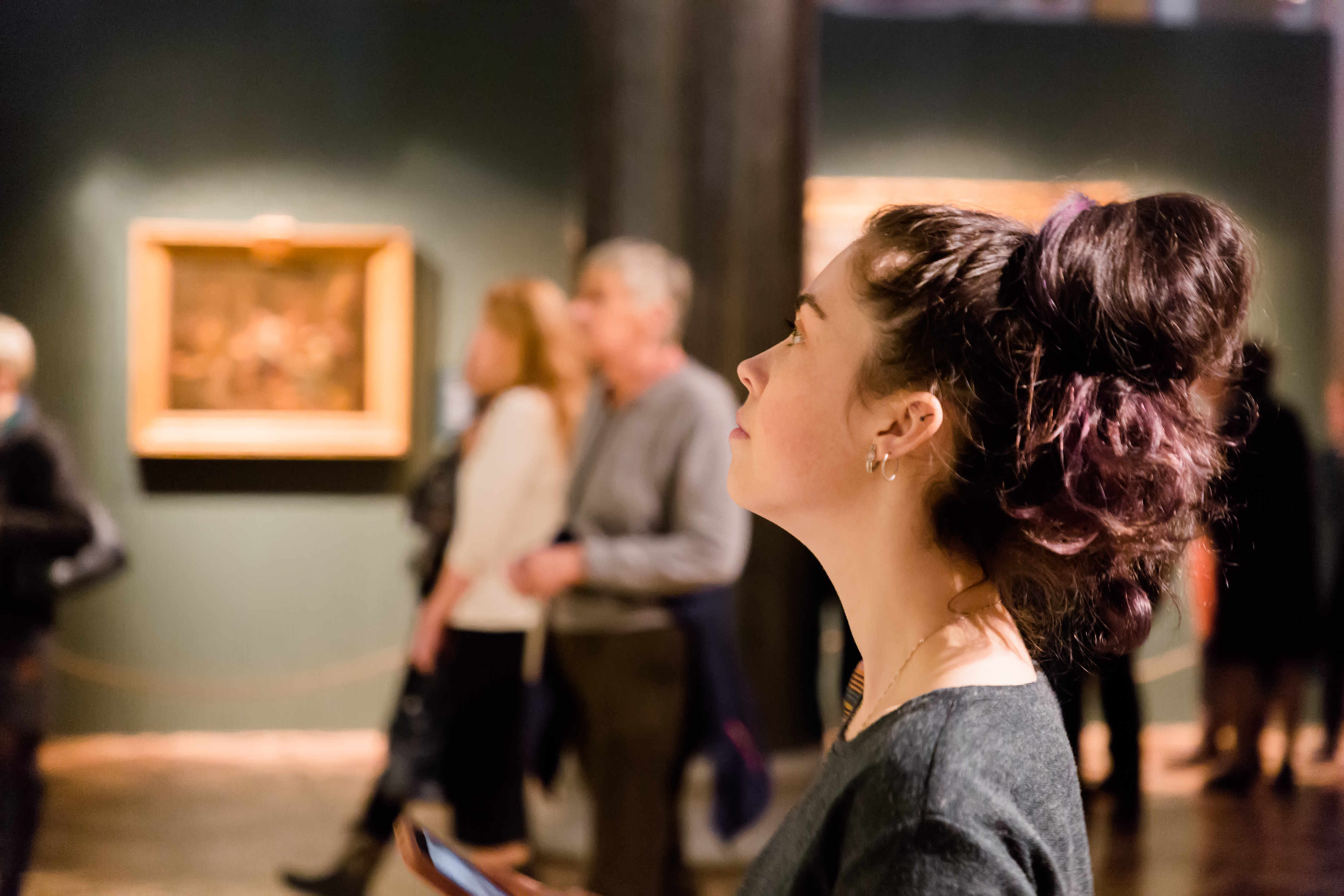 Woman observing art exhibit in a gallery, enhancing cultural experience in a travel tour.