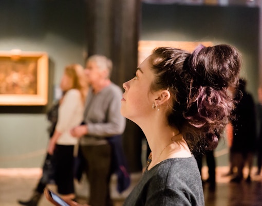 Woman observing artwork at a museum exhibition.