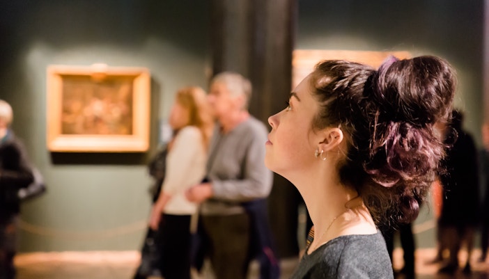 Woman observing art exhibit in a gallery, enhancing cultural experience in a travel tour.
