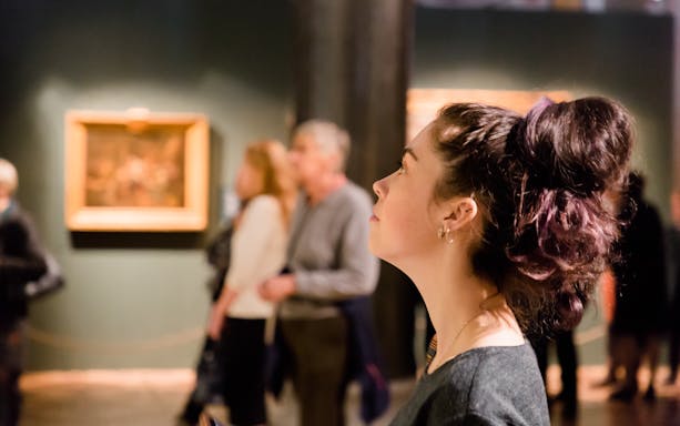 Woman observing artwork at a museum exhibition.